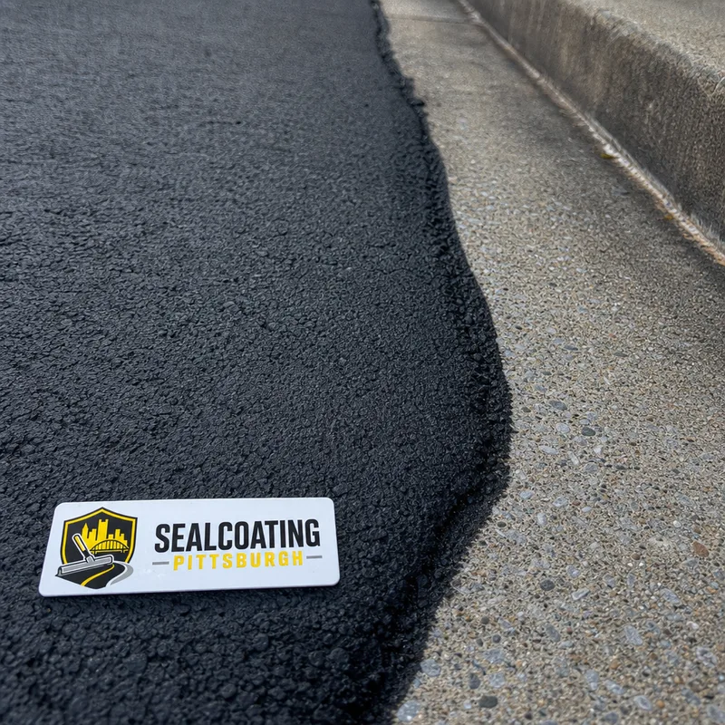 Close-up of evenly sealed asphalt with clean edging beside a concrete sidewalk and curb